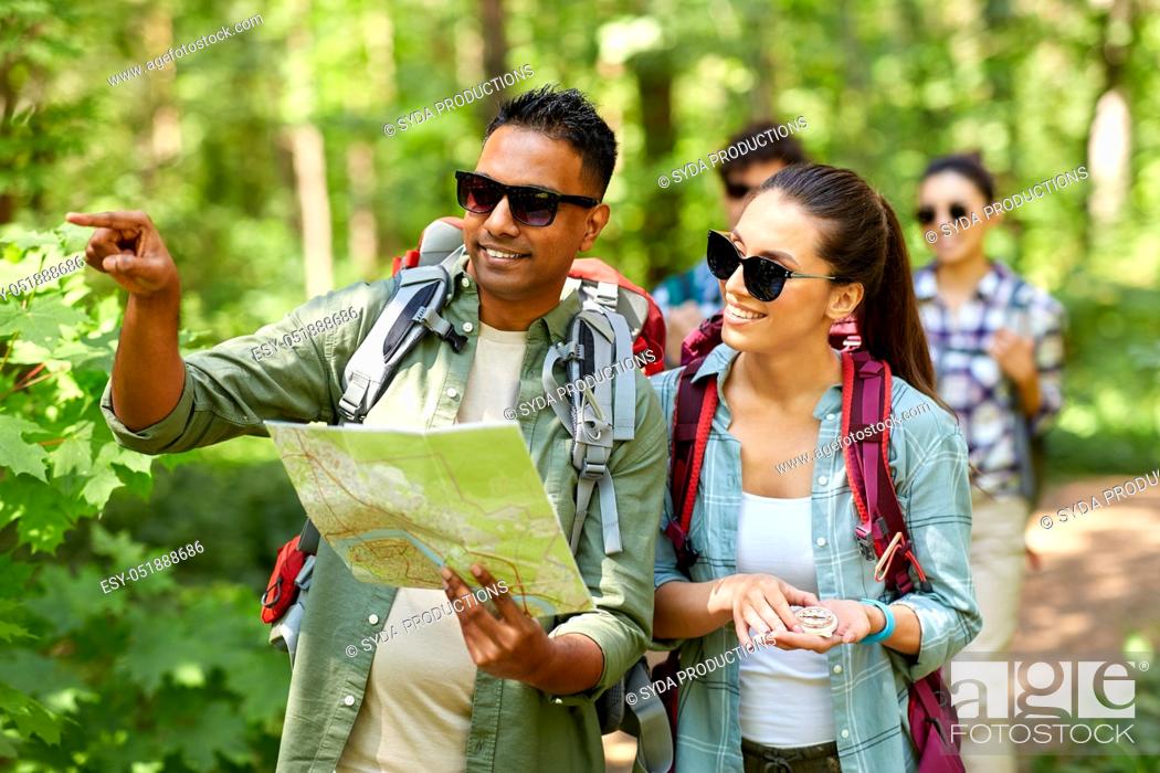 Stock Photo: friends with map and backpacks hiking in forest.
