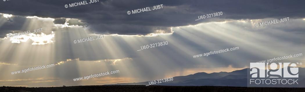 Stock Photo: Stormy skies pass through the Southern Utah landscape and produce sunbeams at sunset.