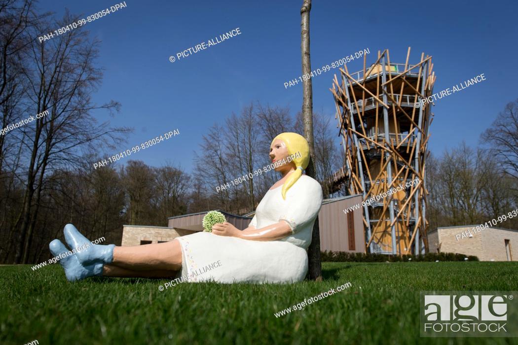 Stock Photo: 10 April 2018, Germany, Bad Iburg: A figure sits in front of the National Garden Show's main attraction, the 'Treetop Path'.