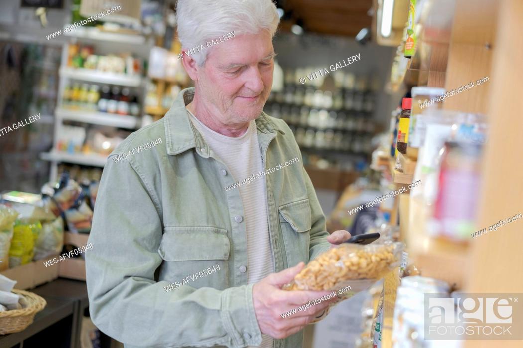 Stock Photo: Senior man buying groceries in a small food store.