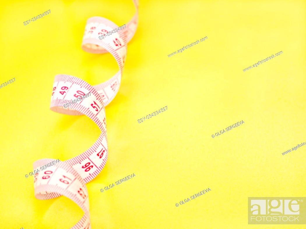 Stock Photo: Red and white measuring tape on yellow background.
