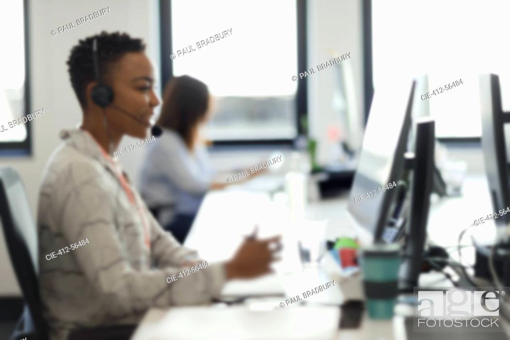 Stock Photo: Businesswoman in headset working at computer in call center office.