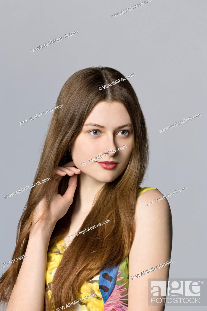 Stock Photo: Beautiful woman looking away against gray background.