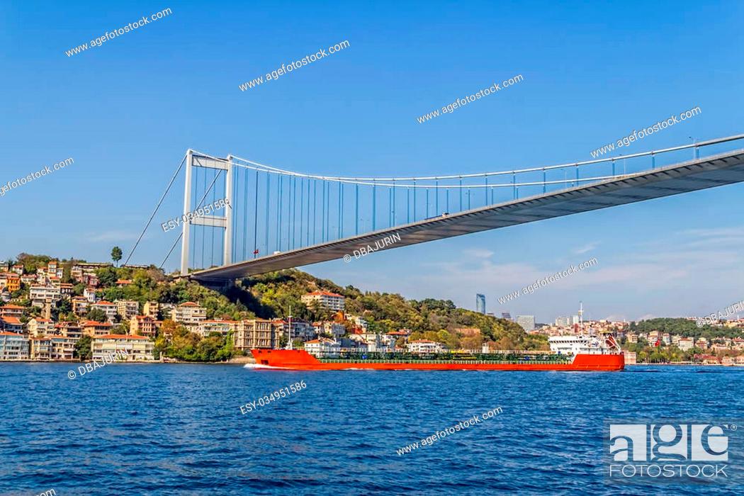 Stock Photo: Long red transport ship sailing under the Fatih Sultan Mehmet Bridge.