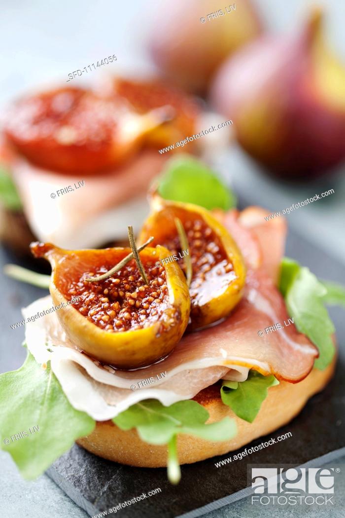 Stock Photo: Crostini topped with rocket, raw ham, oven-baked balsamic figs and rosemary.