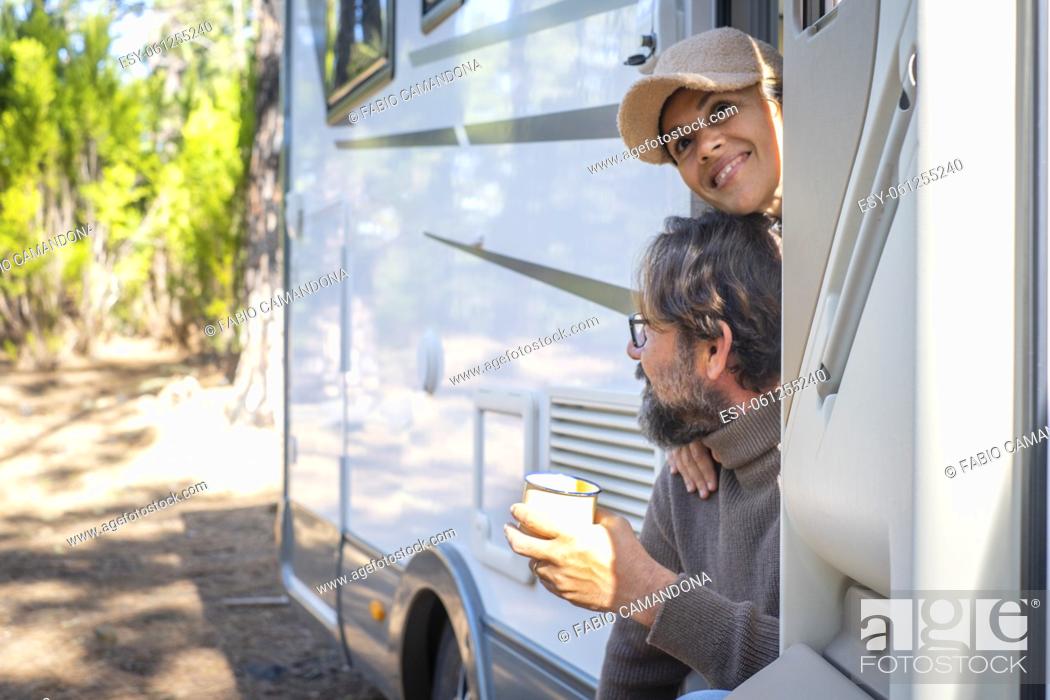 Stock Photo: Young couple of tourists with camper motor home sitting at the door enjoing nature outdoors leisure feeling. Travel people and mountains destination concept.