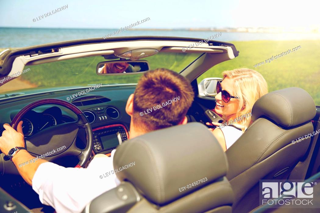 Stock Photo: leisure, road trip, dating, couple and people concept - happy man and woman driving in cabriolet car outdoors.