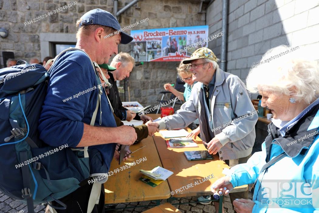 Stock Photo: 22 May 2022, Saxony-Anhalt, Schierke: Record hiker Benno Schmidt, alias Brocken-Benno, signs books during a ceremony. The record hiker celebrated his 9000th.