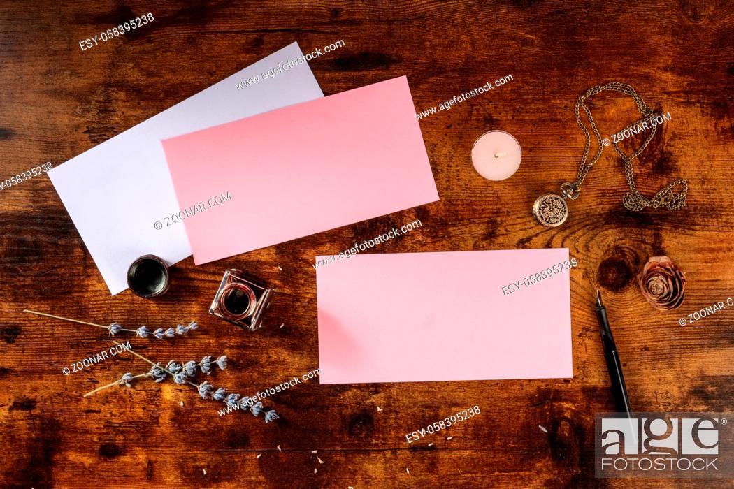 Stock Photo: Pink mockup for an invitation or greeting card, shot from the top on a dark rustic wooden background.