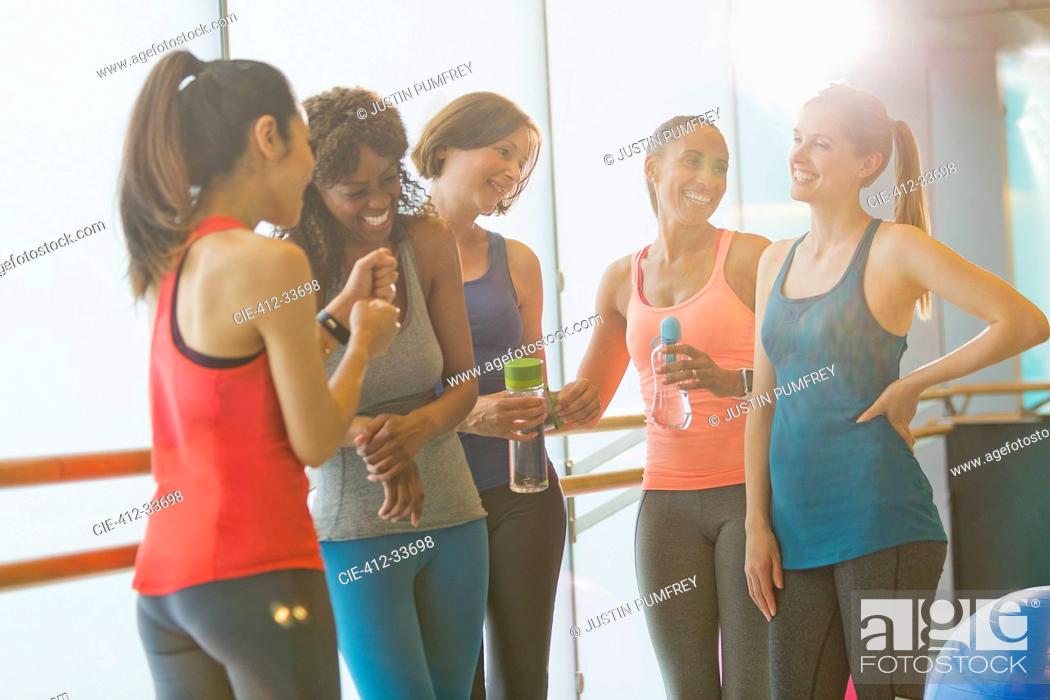 Stock Photo: Smiling women talking and drinking water in sunny gym studio.