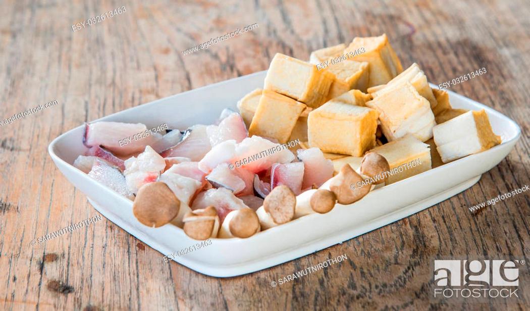 Stock Photo: Meat, fish, mushroom and tofu dish in white placed on a wooden table. Focus on fish.