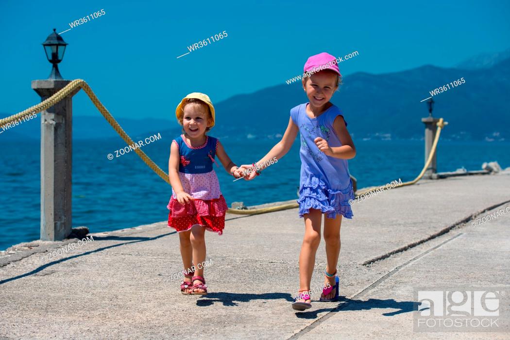 Stock Photo: Happy smiling little sisters having fun holding their hands while running on the beach coast during Summer vacation Healthy childhood lifestyle concept.