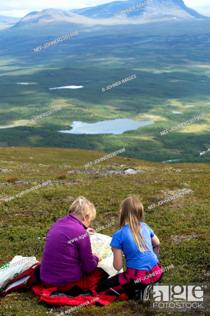 Stock Photo: Girls reading map in mountains.