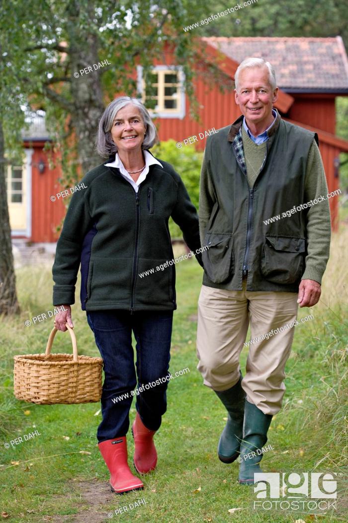 Stock Photo: Senior couple walking with holding basket, smiling.