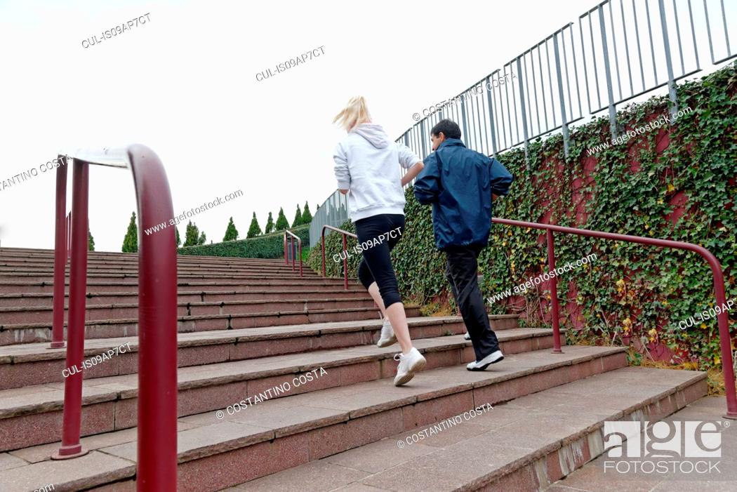 Stock Photo: Man and woman running up steps together, rear view.