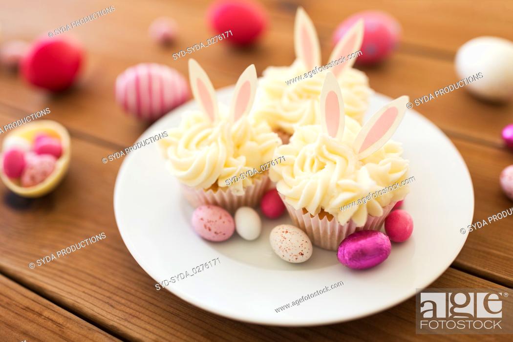 Stock Photo: cupcakes with easter eggs and candies on table.