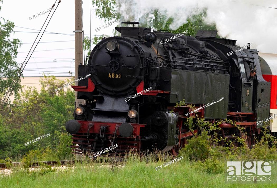 Stock Photo: Historic steam locomotive with passenger wagons speeding on railroad tracks curve and blowing heavy white smoke near Sofia.