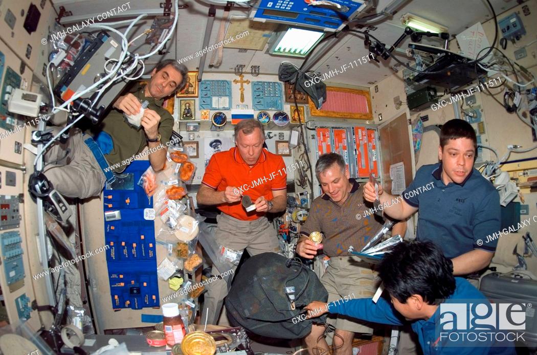Stock Photo: The STS-123 and Expedition 16 crewmembers share a meal near the galley in the Zvezda Service Module of the International Space Station while Space Shuttle.