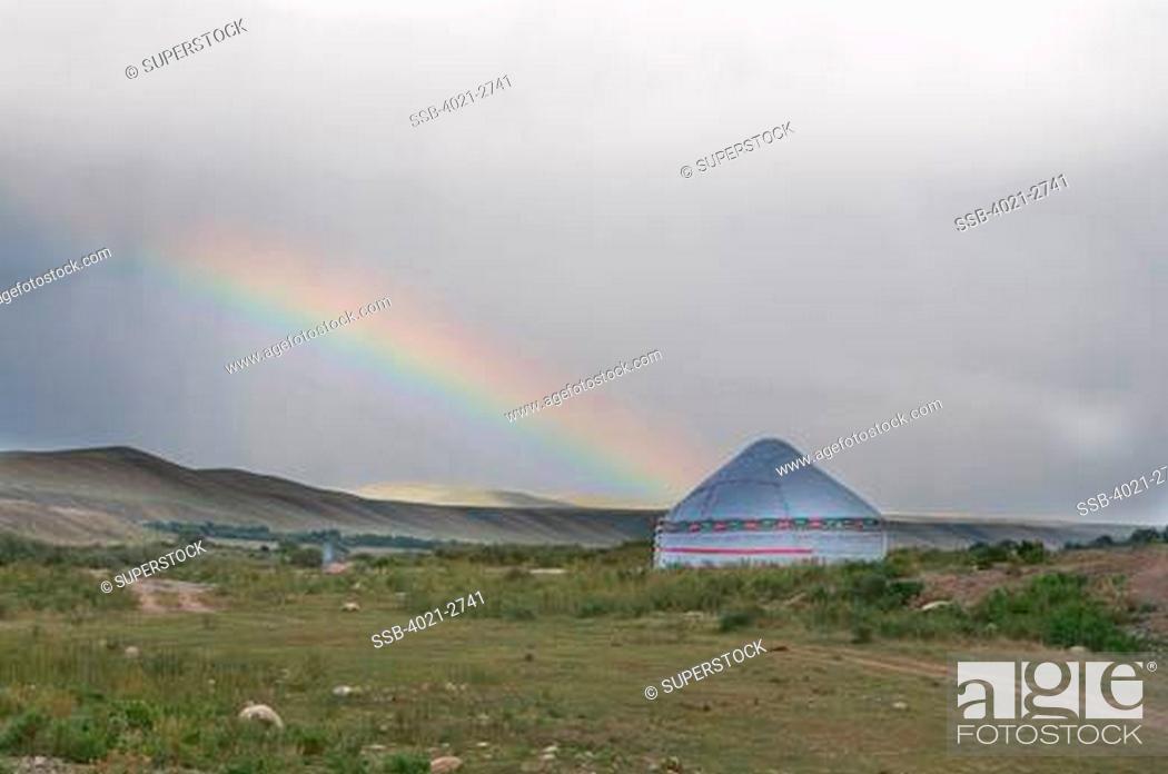Stock Photo: Kyrgyzstan, between Sary Chelek and Bishkek, Rainbow and tent in barren landscape.