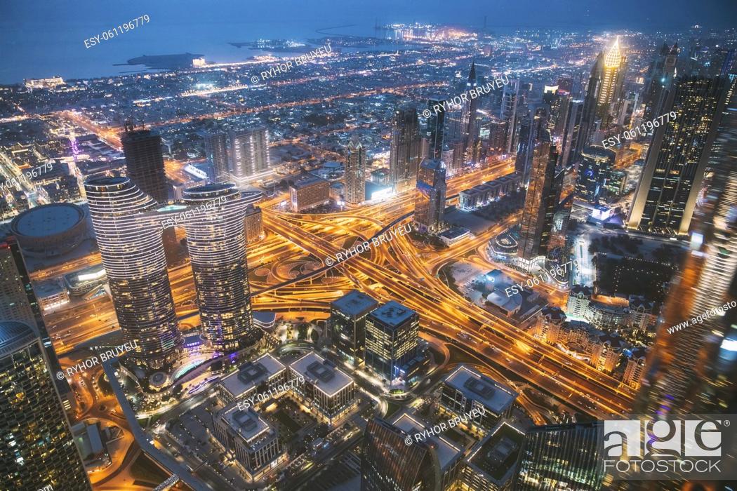 Stock Photo: Aerial View Of Evening Night Scenic View Of Skyscraper In Dubai. Street Night Traffic In Residential District. Waterfront And Dubai Cityscape In Summer Evening.
