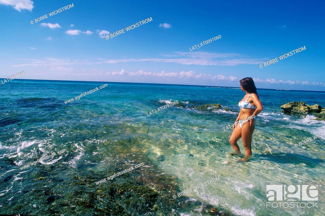 Stock Photo: Beach. Young woman in bikini. Standing in clear shallow water.