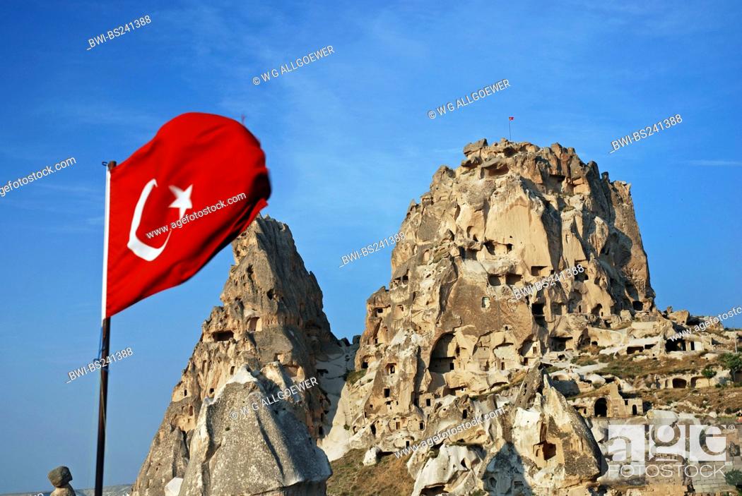 Stock Photo: historical cave architecture built into tuff formations with the turkish flag waving in the foreground, Turkey, Cappadocia, Uchisar.