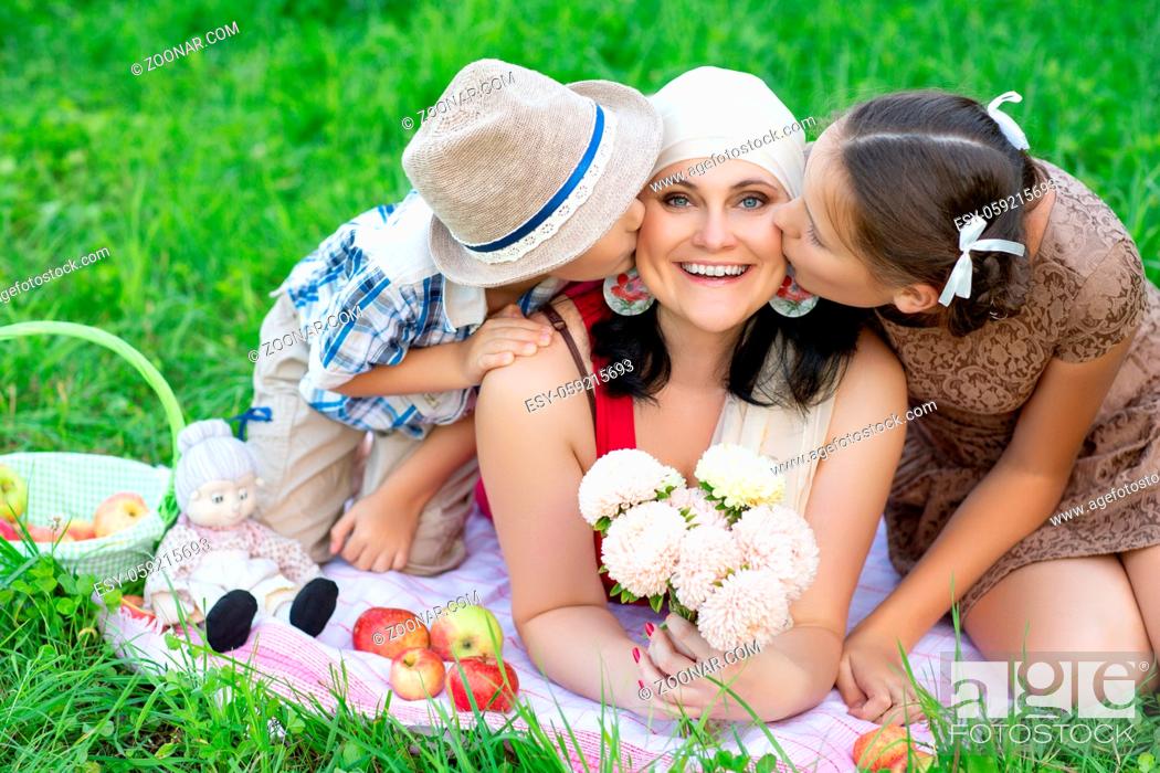 Stock Photo: beautiful mother with son and daughter having picnic on grass. oudoor shot.
