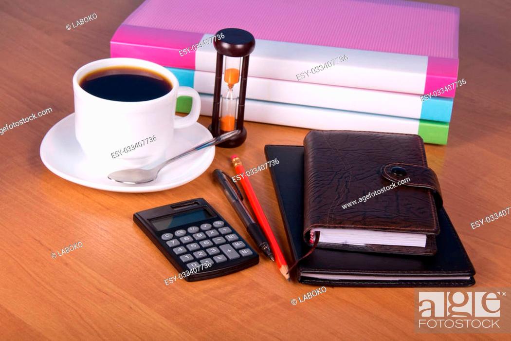 Stock Photo: Notepad, organizer, pencil and pen, folders for documents the calculator, hourglasses and a cup of coffee on a table.