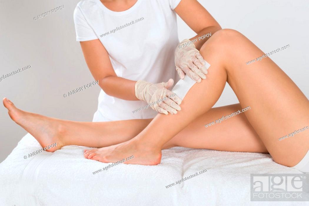 Stock Photo: Beautician Waxing Leg Of Woman With Wax Strip At Beauty Clinic.