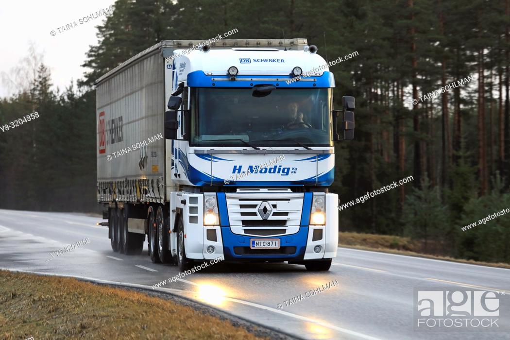 Stock Photo: SALO, FINLAND - DECEMBER 8, 2017: Blue and white Renault Magnum truck of Helmer Modig Oy pulls DB Schenker trailer along wet highway in early winter.
