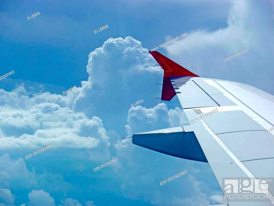 Stock Photo: wing of an airbus with red winglet at flight before clouds.