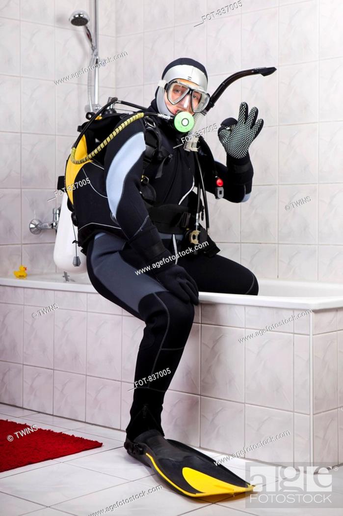 Stock Photo: A scuba diver making the OK sign while sitting on the edge of a bathtub.