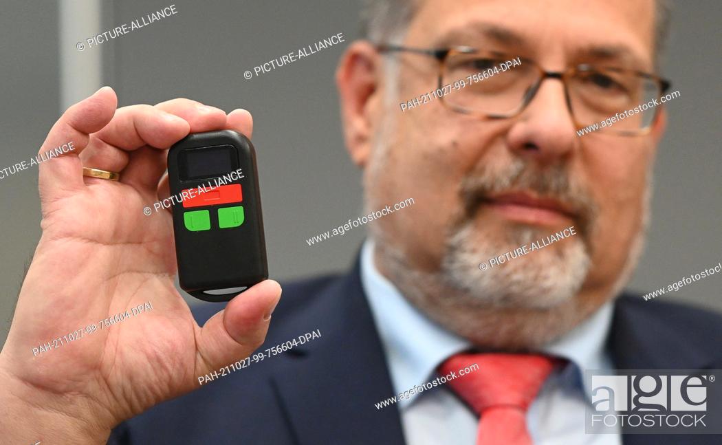 Stock Photo: 27 October 2021, Hessen, Kassel: Ralf Selbmann, security officer at the Ministry of Justice of Baden-Wuerttemberg, shows an alarm device for bailiffs.