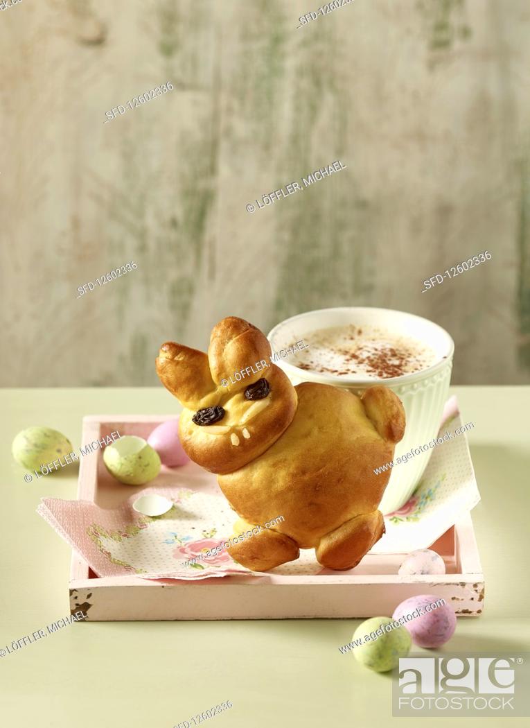 Stock Photo: A bread Easter bunny with a cup of coffee and colourful quail's eggs.