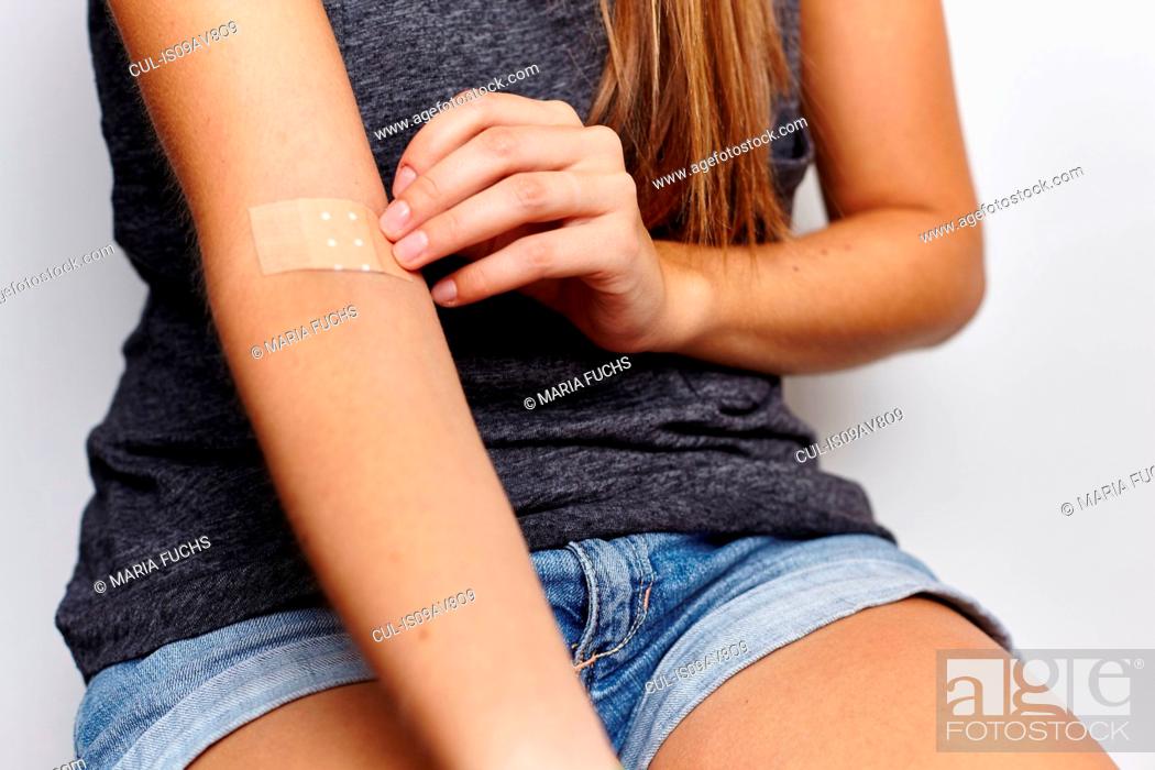 Stock Photo: Woman applying plaster on right arm.