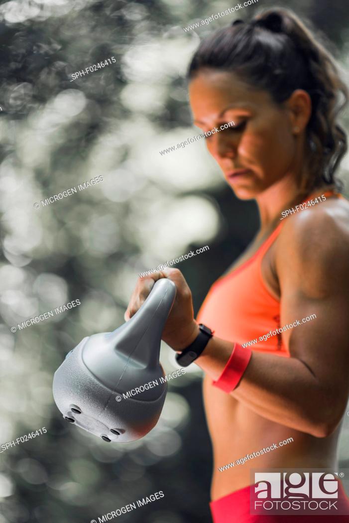 Stock Photo: Outdoor exercising. Female athlete exercising with kettlebell in the park.