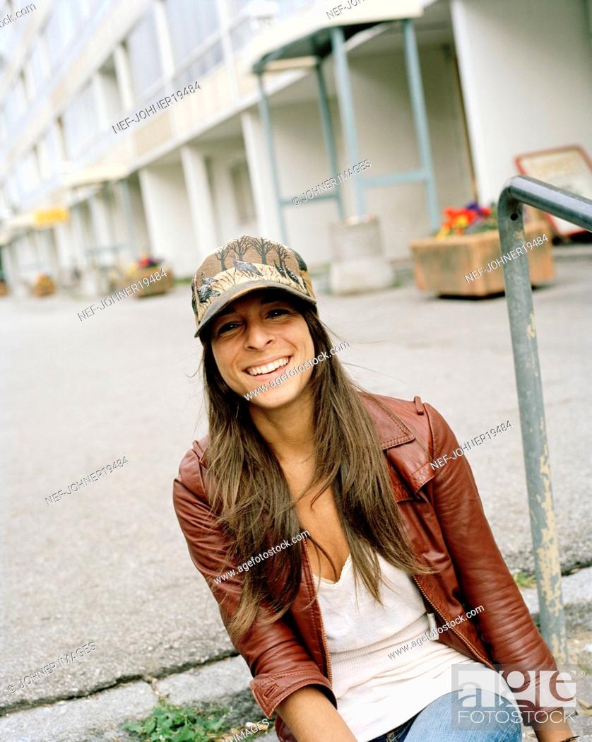 Stock Photo: Looking At Camera, Long Hair, Color Image, Only, One, Outdoors, People, Portrait, Summer, Vertical, Woman, Happy, Positive, Smile, Laughing, Brunette, Cap, Teenager, Friendly, House, Building, Individuality, Confidence, Area, Trendy, Sweden, Optimism, Apartment, Flat, Attitude