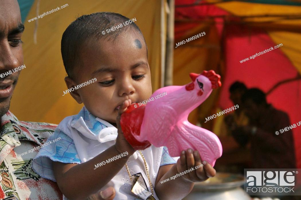 Stock Photo: A Muslim child playing with the clay model of a cock at a fair during Eid-ul-Adha festival in a village Mayshaghuni, Rupsha, Khulna, Bangladesh January 01.