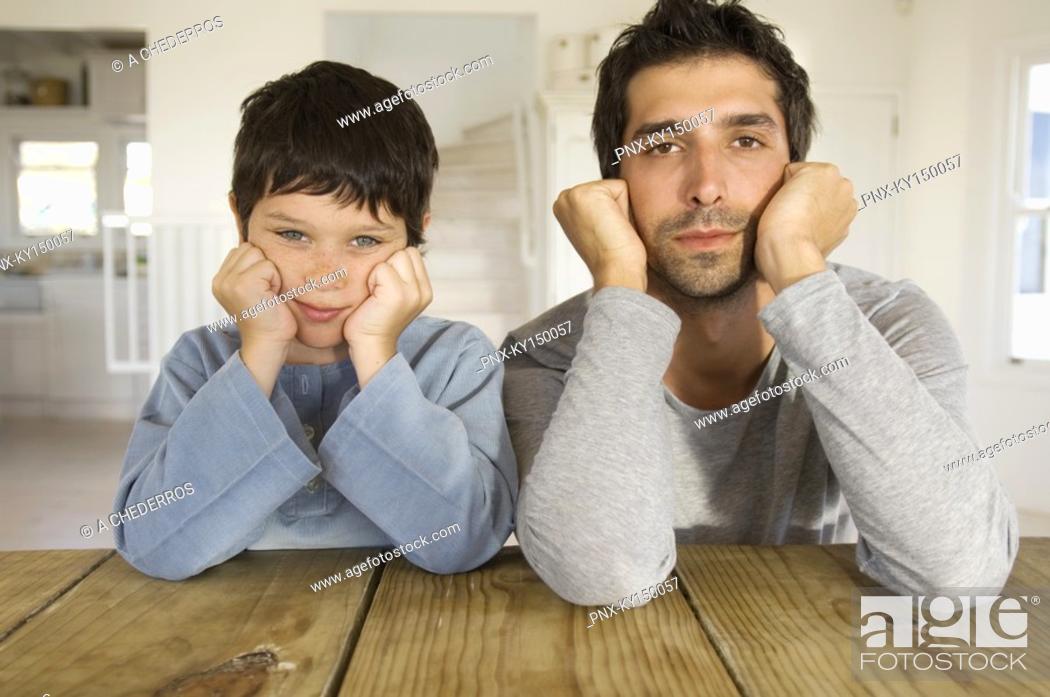 Stock Photo: Father and son looking at camera, with hands on cheeks.
