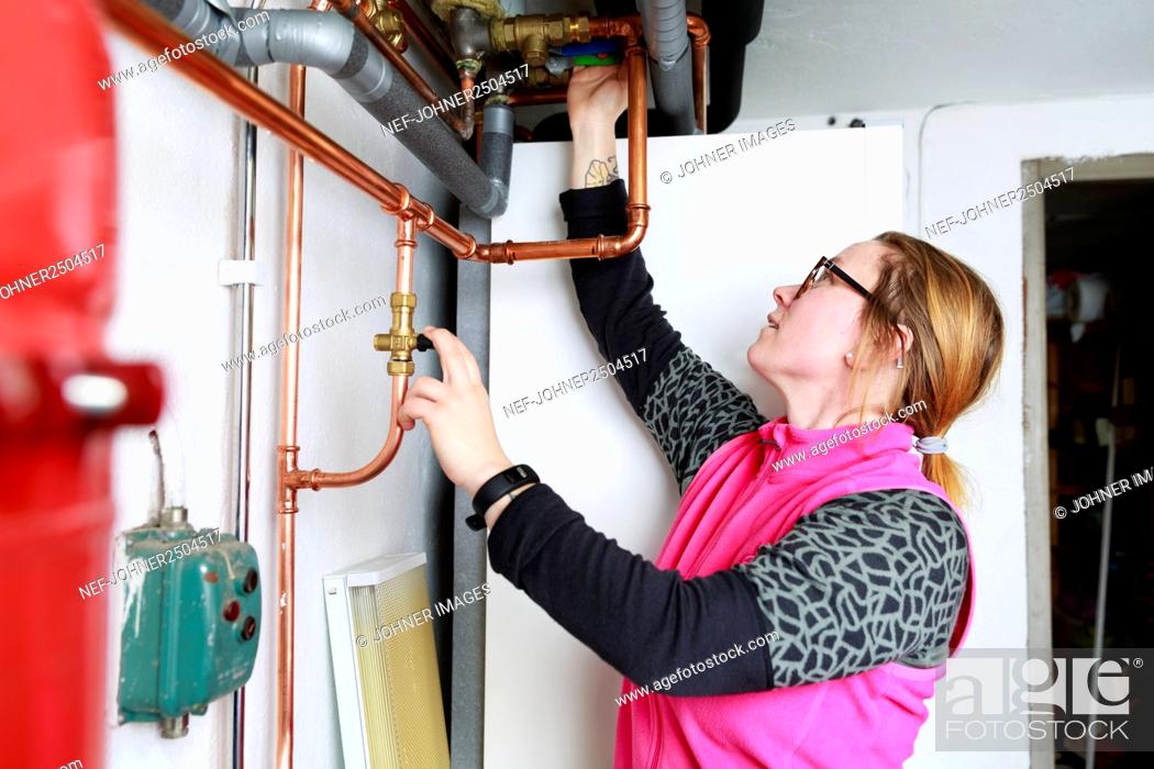 Stock Photo: Female plumber checking pipes.