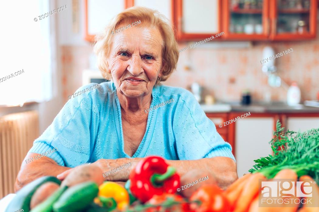 Stock Photo: Happy senior woman at home with fresh crop from her garden.