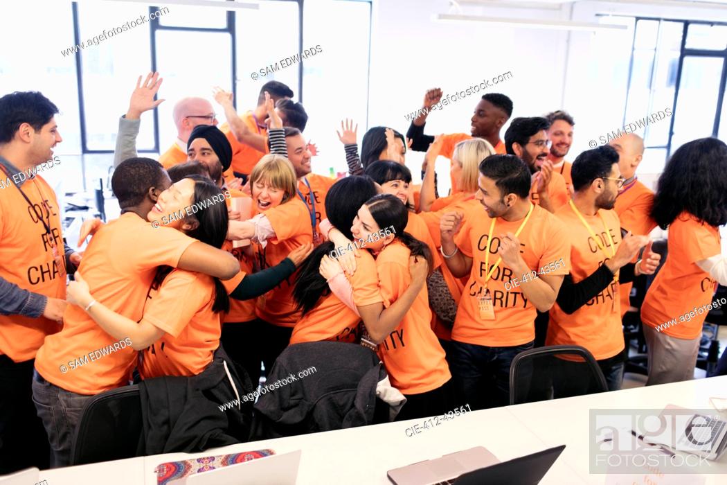 Stock Photo: Enthusiastic hackers celebrating, coding for charity at hackathon.