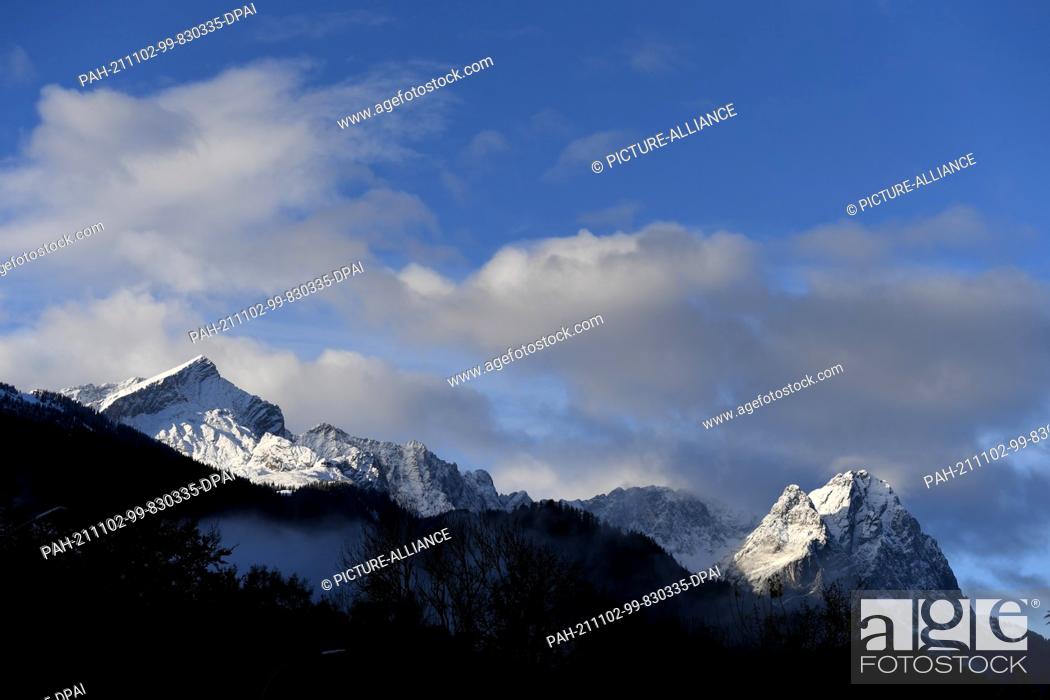 Stock Photo: 02 November 2021, Bavaria, Garmisch-Partenkirchen: Freshly covered with snow after the night, the summits of the Wetterstein Mountains with the Alpspitze (l).