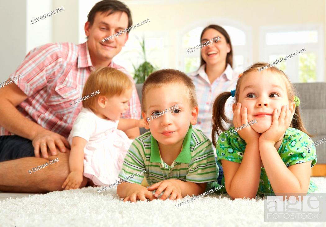 Stock Photo: Happy family with 3 children sitting on floor of living room at home.