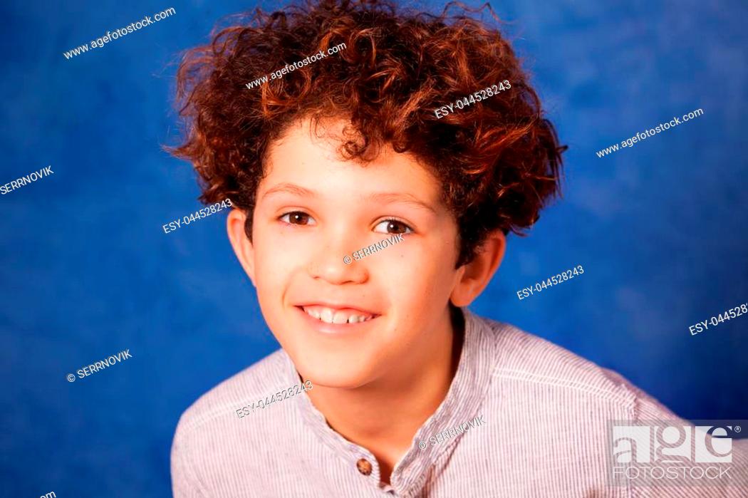 Close-up portrait of smiling preteen boy with curly hair and brown eyes  against blue background, Stock Photo, Picture And Low Budget Royalty Free  Image. Pic. ESY-044528243 | agefotostock