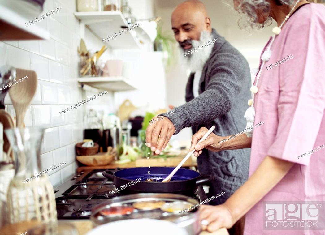 Stock Photo: Couple cooking at kitchen stove.
