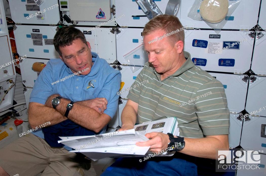 Stock Photo: Astronauts Eric Boe (right), STS-126 pilot, and Steve Bowen, mission specialist, look over a procedures manual on the middeck of Space Shuttle Endeavour while.