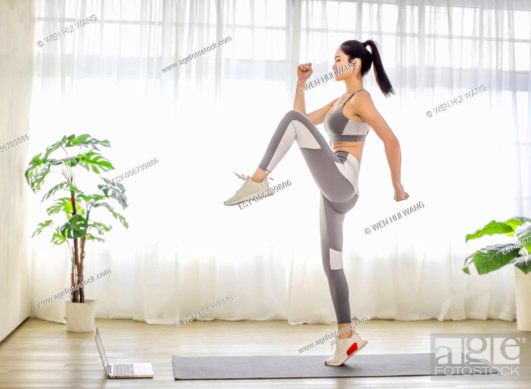 Stock Photo: Young woman in sportswear watching online video with fitness exercises on laptop.