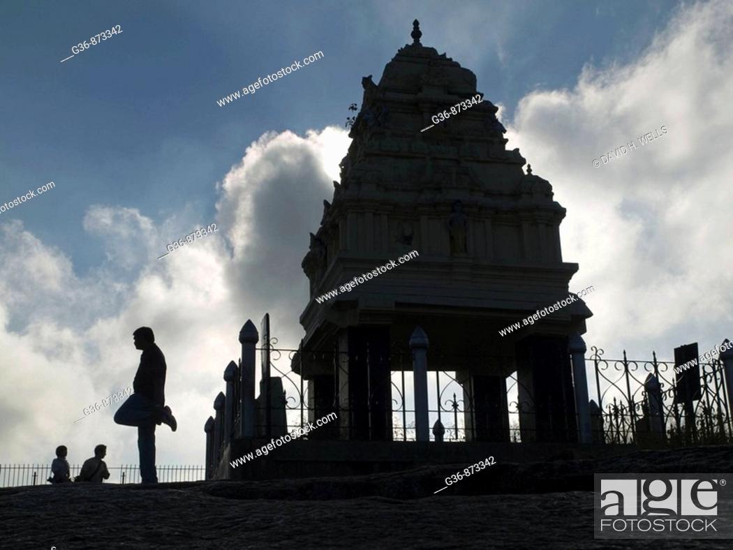 Stock Photo: Visitors pass and exercise near a small shrine atop a large rock in the Lal Bagh park in Bangalore, Karnataka, India.