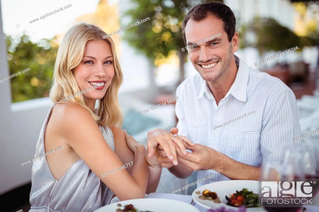 Stock Photo: Man putting engagement ring on womans hand.